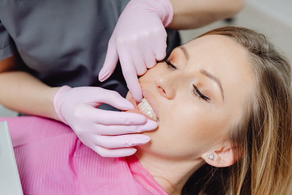 A dentist wearing gloves examines a patient's teeth in a close-up view during a dental check-up.