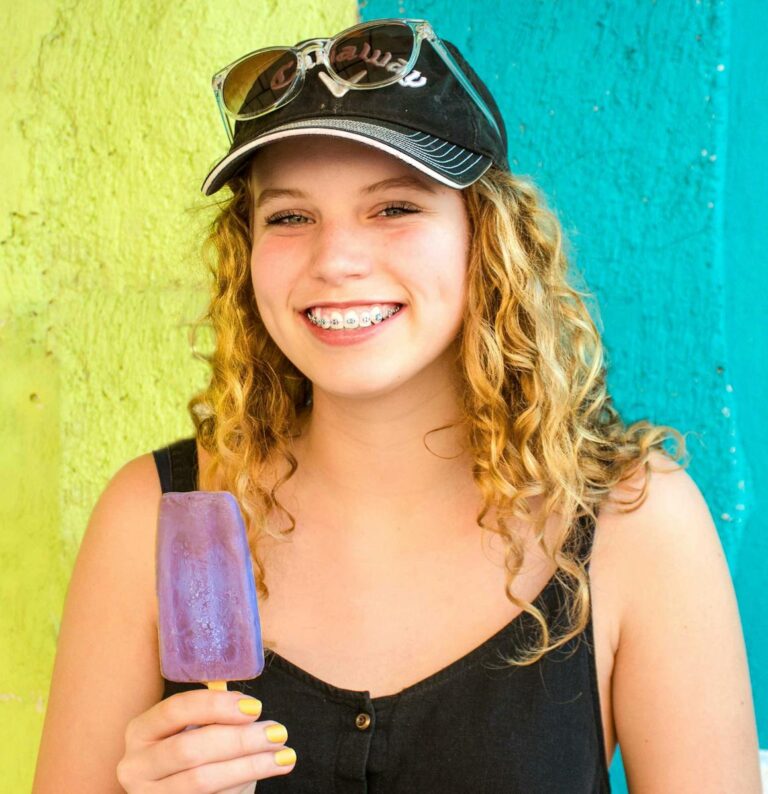 Person wearing braces smiling brightly, representing confidence and comfort during orthodontic treatment.