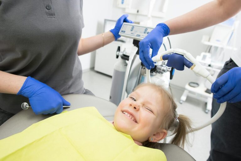 Smiling young child at their first dental checkup with a friendly dentist