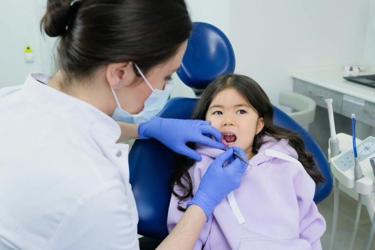 Smiling child sitting calmly in a dental chair with a friendly pediatric dentist